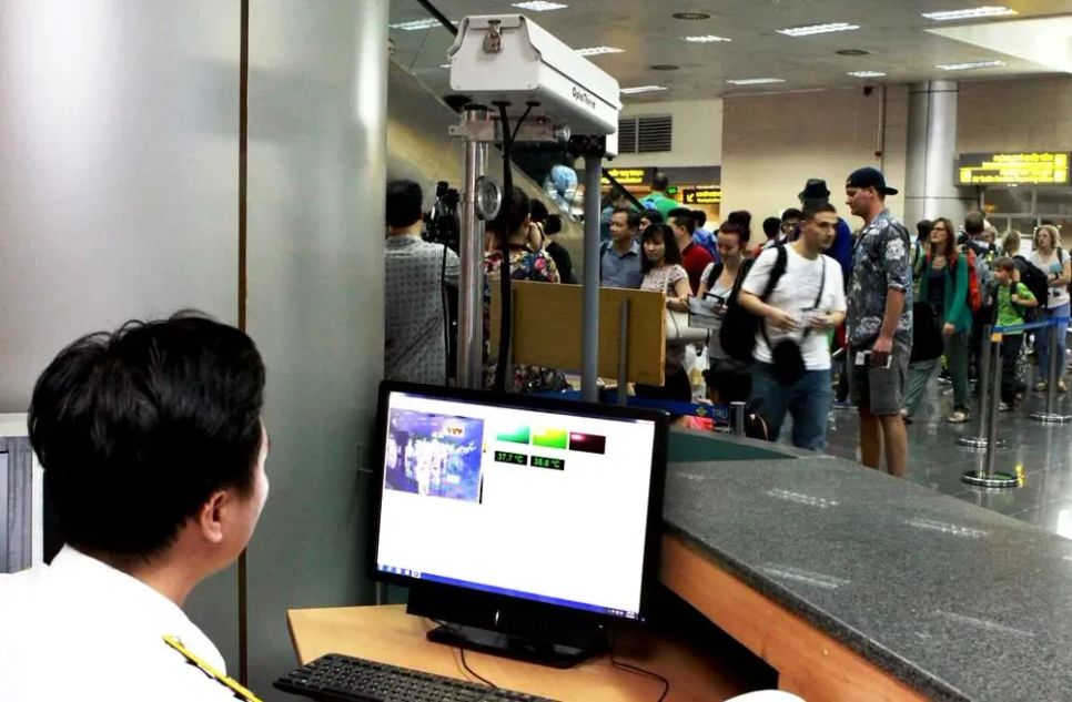 Nhân viên cảng hàng không đang đo thân nhiệt người nhập cảnh