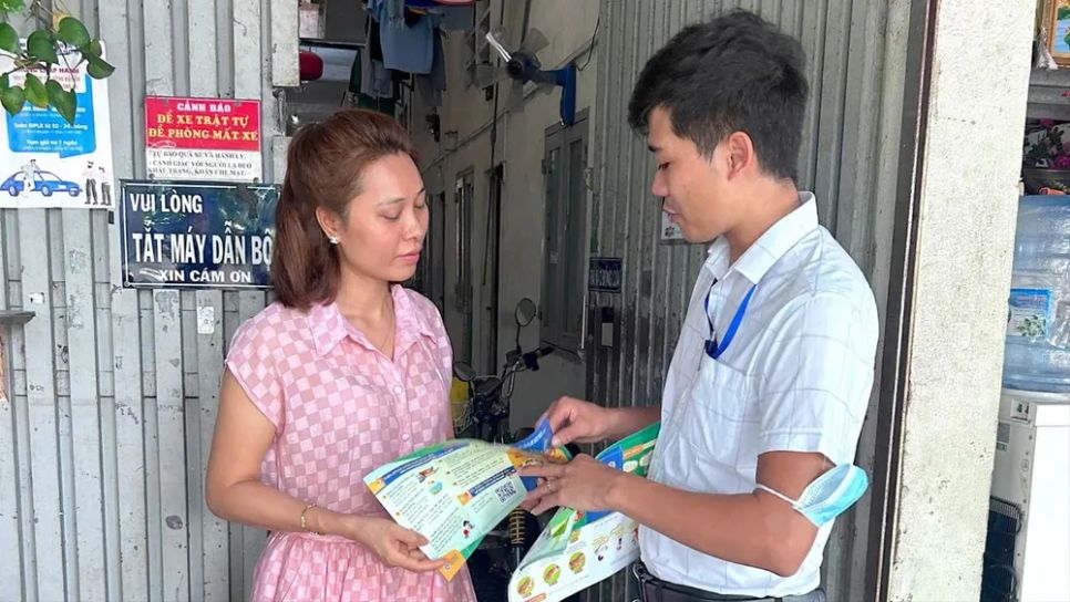 Cộng tác viên cộng đồng sức khỏe phường Linh Xuân phát tờ rơi phòng chống dịch SXH cho người dân. Ảnh: QUANG HUY