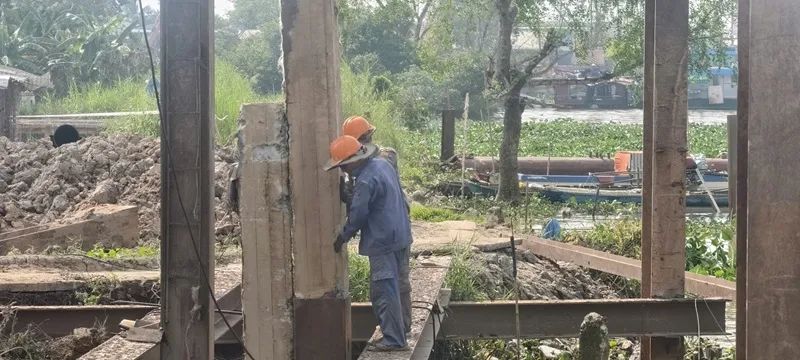 Công nhân được trang bị bảo hộ lao động, nón bảo hộ khi thực hiện đóng cọc kè sông Tiền.