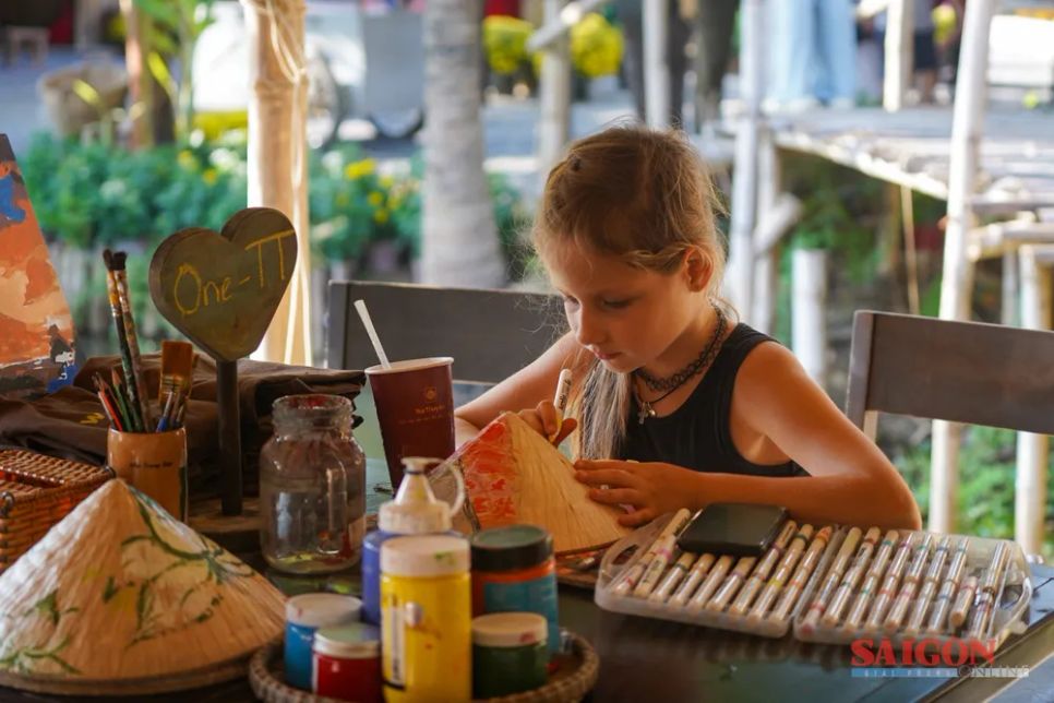 Em bé nước ngoài thích thú vẽ tranh trên nón lá. Ảnh: HIẾU GIANG Em bé nước ngoài thích thú vẽ tranh trên nón lá. Ảnh: HIẾU GIANG