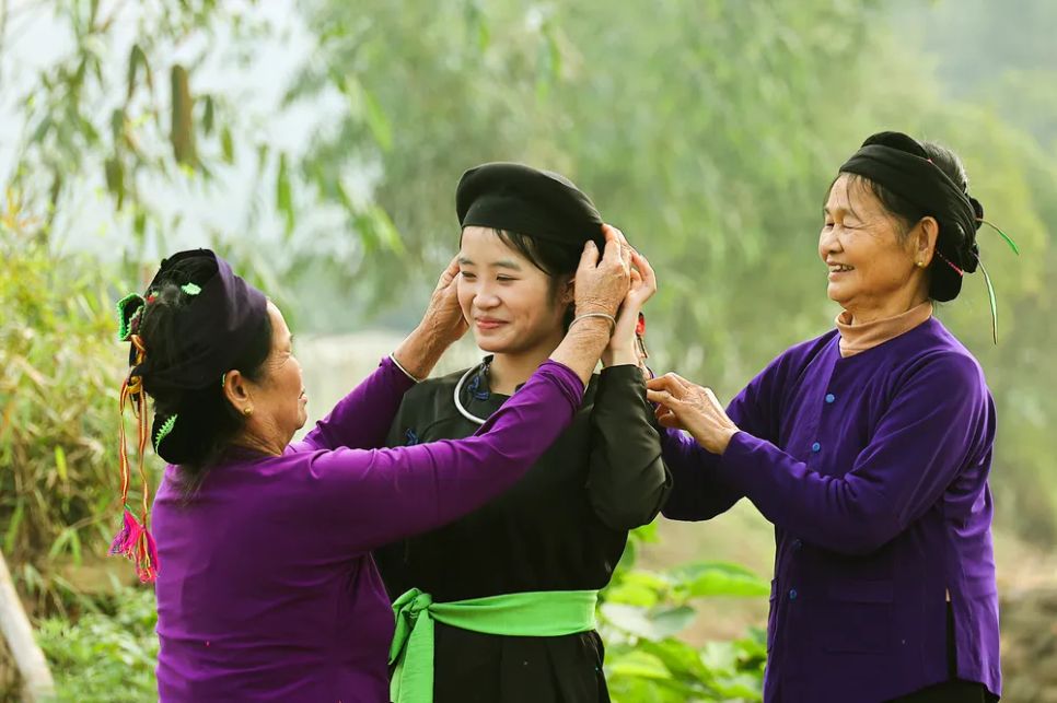 Khoảnh khắc đong đầy yêu thương, khi thế hệ cao niên tận tay chỉnh sửa bộ áo chàm truyền thống cho thiếu nữ Tày. Đây không chỉ là trang phục, mà còn là linh hồn, là câu chuyện của bản sắc được gìn giữ và tiếp nối