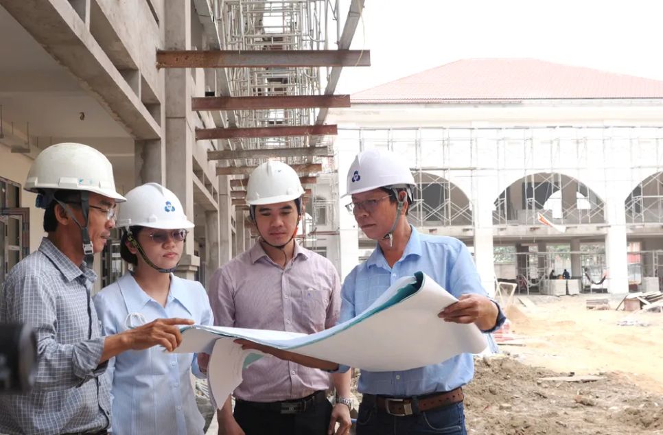 Ông Văn Công Danh, Chỉ huy trưởng công trình, công tác tại Công ty Thương mại dịch vụ Xuân Tân Thành (ngoài cùng bên phải) báo cáo tiến độ dự án Trường Tiểu học Vĩnh Lộc B. Ảnh: HOÀNG HÙNG