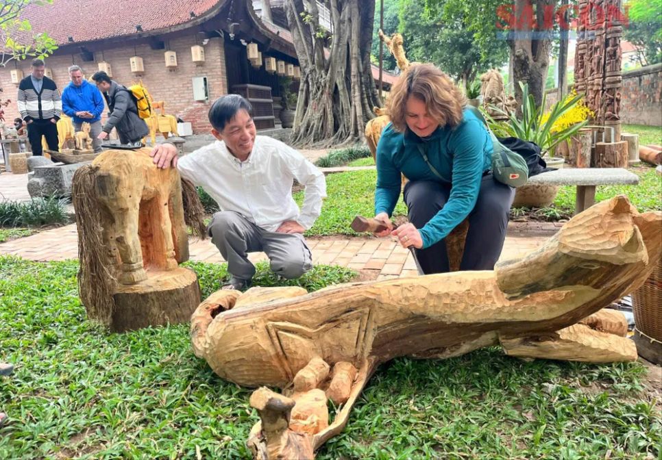 Du khách quốc tế thích thú trải nghiệm đục tượng gỗ theo hình thức văn hoá bản địa Tây Nguyên tại Di tích Quốc gia đặc biệt Văn Miếu - Quốc Tử Giám