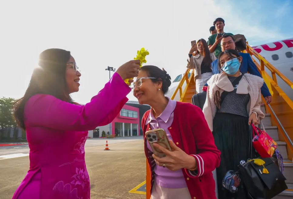 Bà Nguyễn Thị Anh Thi tặng vòng hoa chào đón khách trên chuyến bay đầu tiên đến Đà Nẵng sáng 25-2