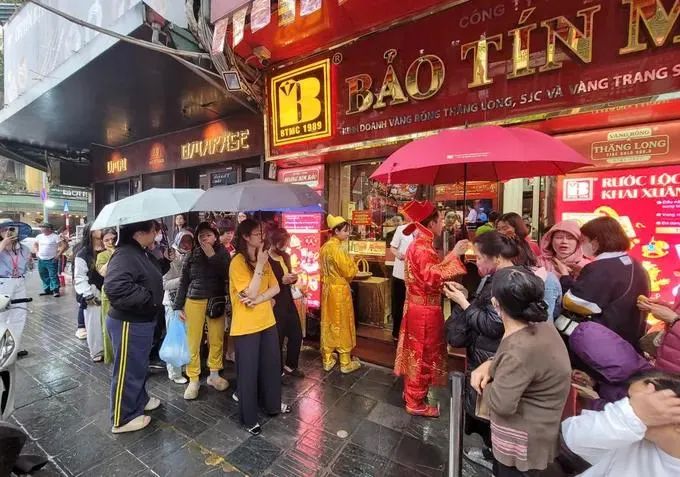 Dù trời mưa lạnh nhưng nhiều người vẫn kiên trì xếp hàng chờ mua vàng ở phố Trần Nhân Tông. Ảnh: QUỐC KHÁNH