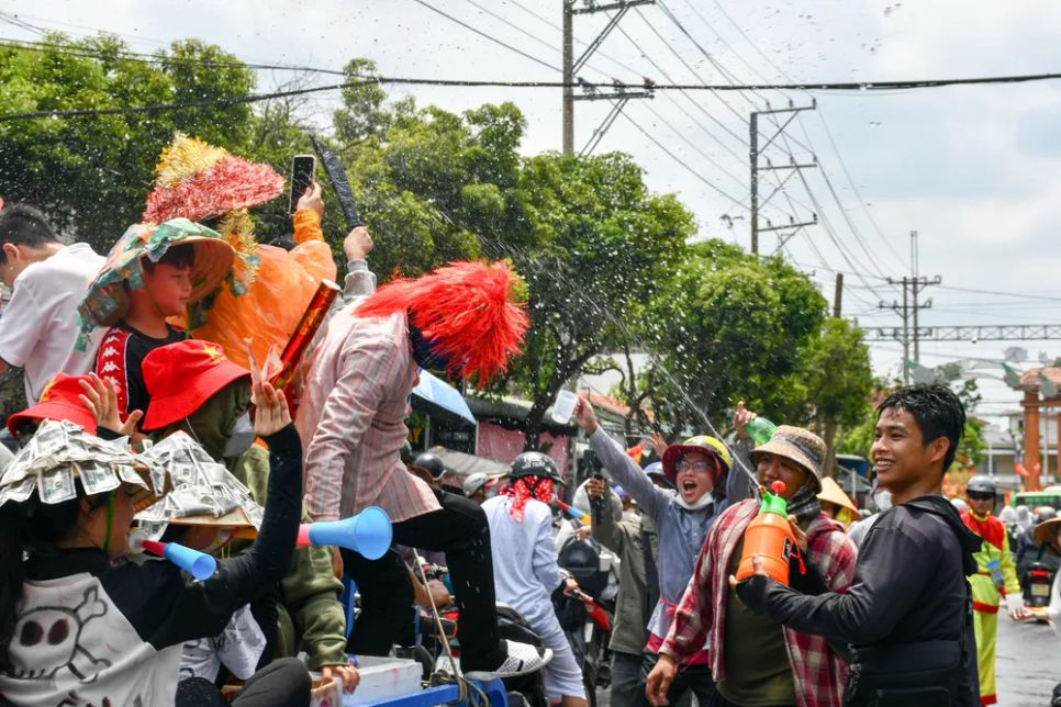 Một thanh niên tưới nước vào những người tham gia giao thông với ý nghĩa cầu may mắn cho năm mới Một thanh niên tưới nước vào những người tham gia giao thông với ý nghĩa cầu may mắn cho năm mới