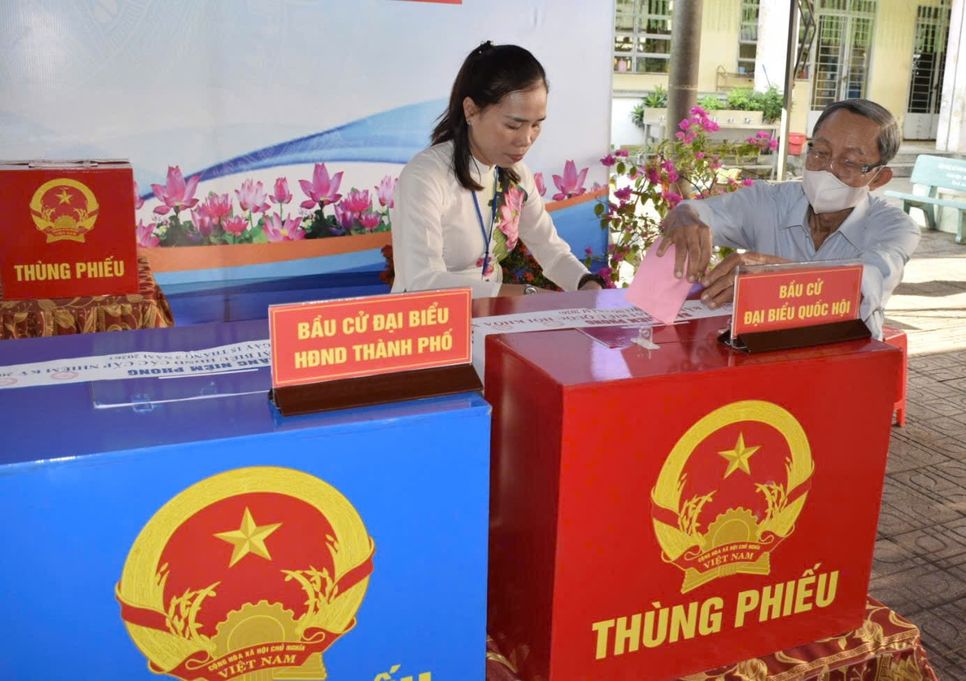 Cán bộ hướng dẫn người lớn tuổi bỏ phiếu theo đúng từng thùng tại phường Tân Đông Hiệp