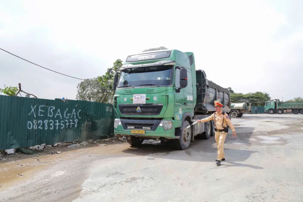 Lực lượng cảnh sát giao thông xử lý các xe tải chở đất thải làm rơi xuống đường. Ảnh: NGUYỄN TIẾN