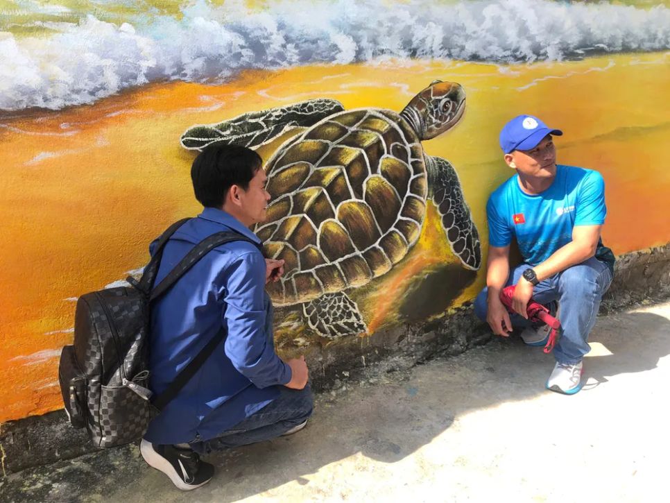 Chụp ảnh cùng với những bức bích họa. Ảnh: ĐÌNH NHỰT