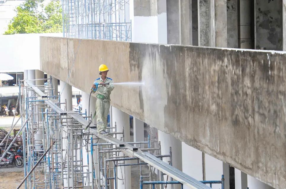 Công nhân rửa các khối tường đã đóng rong rêu đen xì theo thời gian