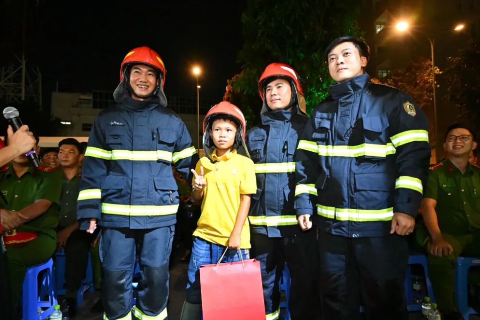 Bé trai chụp hình lưu niệm cùng cán bộ, chiến sĩ Cảnh sát PCCC-CNCH Công an TPHCM. Ảnh: VIỆT DŨNG
