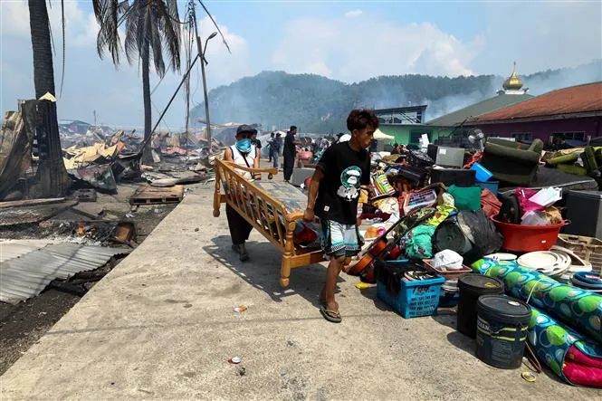 Người dân di chuyển đồ đạc sau vụ hỏa hoạn tại làng chài ven biển ở bang Sabah, trên đảo Borneo, Malaysia. Ảnh: THX