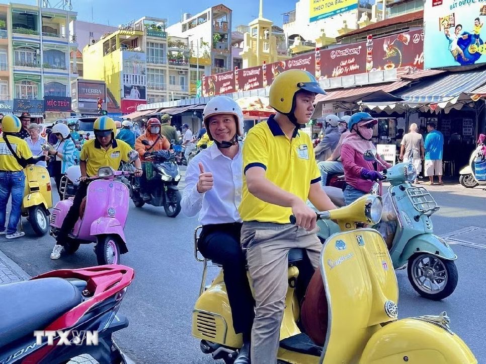 Du khách hào hứng trải nghiệm du lịch TPHCM bằng xe Vespa. (Ảnh: Mỹ Phương/TTXVN)