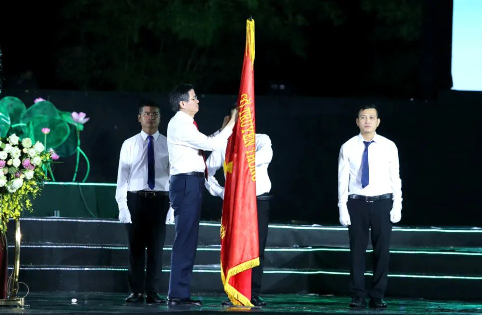 <p> Đồng chí Đoàn Minh Huấn gắn Huân chương Lao động hạng Nhất lên cờ truyền thống của Khu Di tích Kim Liên </p>