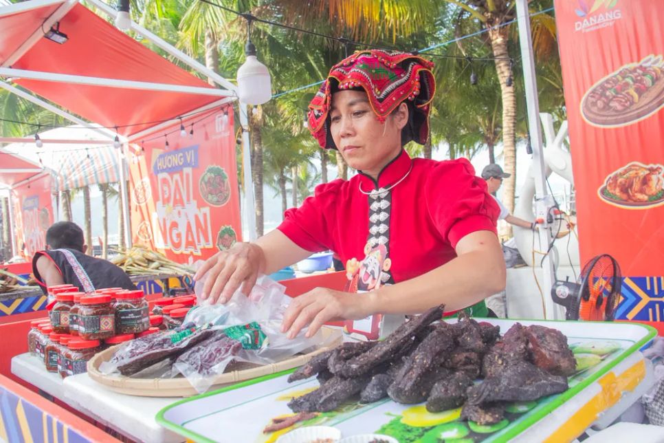 Bà Lù Thị Hạnh (45 tuổi, tỉnh Đắk Lắk) giới thiệu thịt gác bếp và muối chẩm chéo cùng xôi của đồng bào Thái