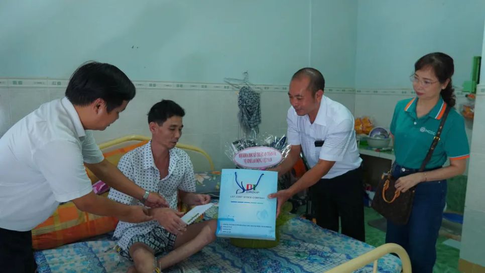 Đoàn công tác trao quà cho người bị tai nạn lao động.
