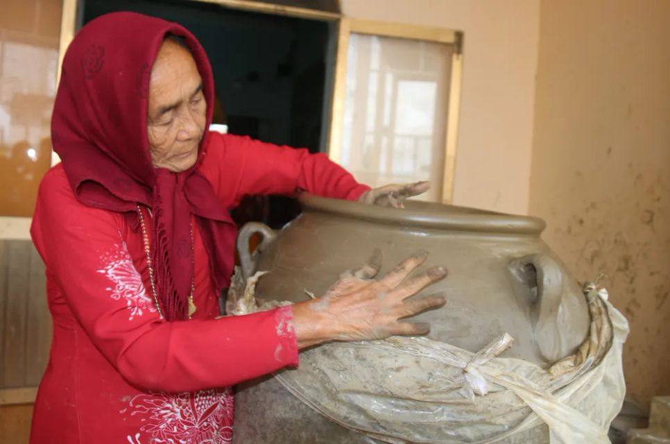 Nghệ nhân vừa dùng tay vuốt đất, vừa đi giật lùi quanh khối gốm để tạo hình sản phẩm. Ảnh: TIẾN THẮNG