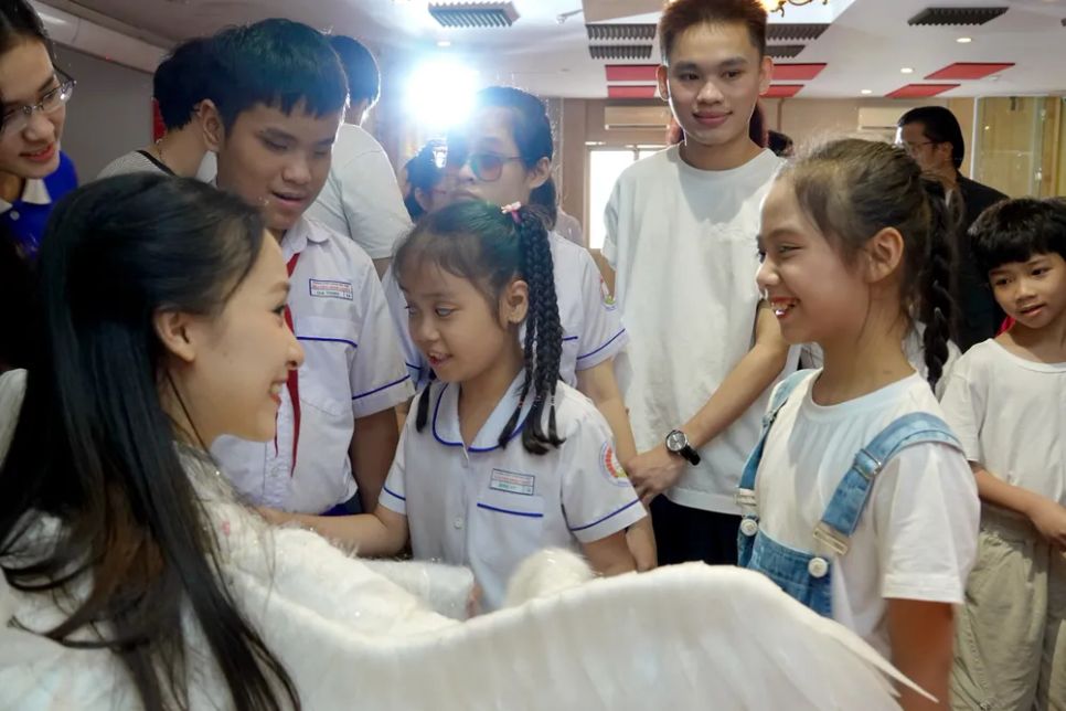 Các em khiếm thị chạm vào đôi cánh chim do diễn viên HTV hóa trang. Ảnh: THÚY BÌNH