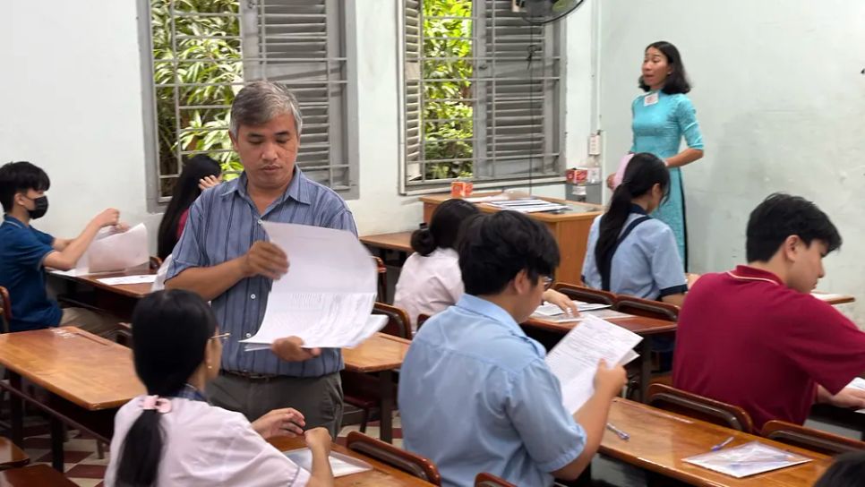 Cán bộ coi thi phát giấy thi cho thí sinh trước giờ làm bài tại điểm thi Trường THPT Chuyên Lê Hồng Phong (phường Chợ Quán, TPHCM). ẢNH: HOÀNG HÙNG