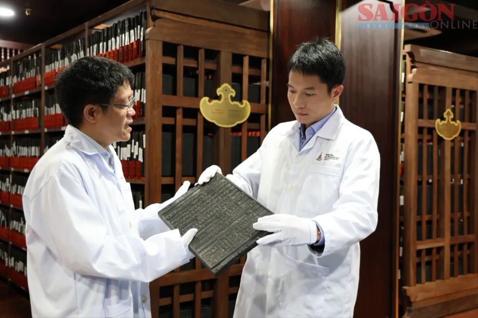 Giám đốc Trung tâm Lưu trữ quốc gia IV Nguyễn Xuân Hùng (trái) kiểm tra tấm mộc bản đang lưu trữ tại trung tâm. Ảnh: NINH GIANG